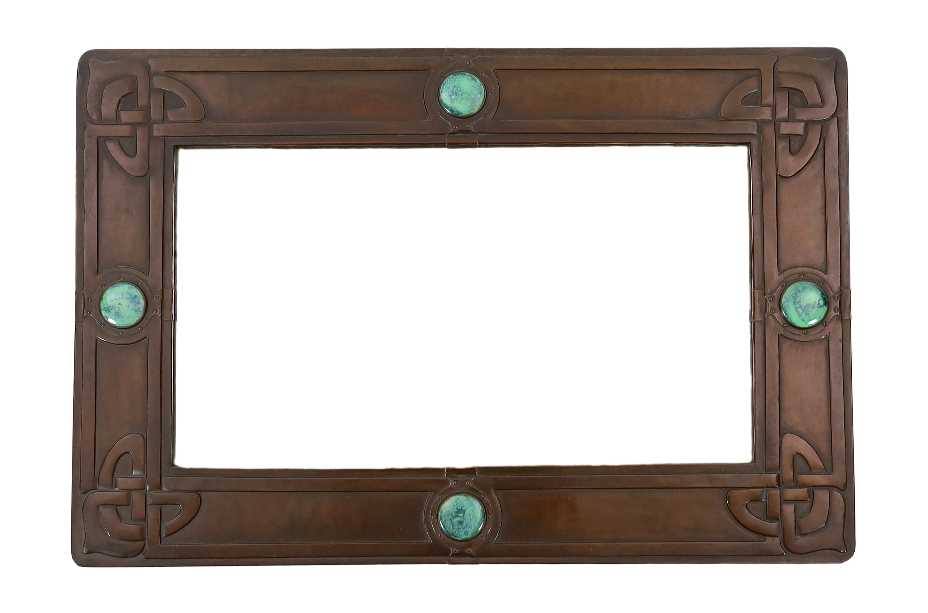 A Liberty Arts & Crafts embossed copper and 'Ruskin stone' wall mirror, designed by Archibald Knox, 91.5cm wide, 61cm high